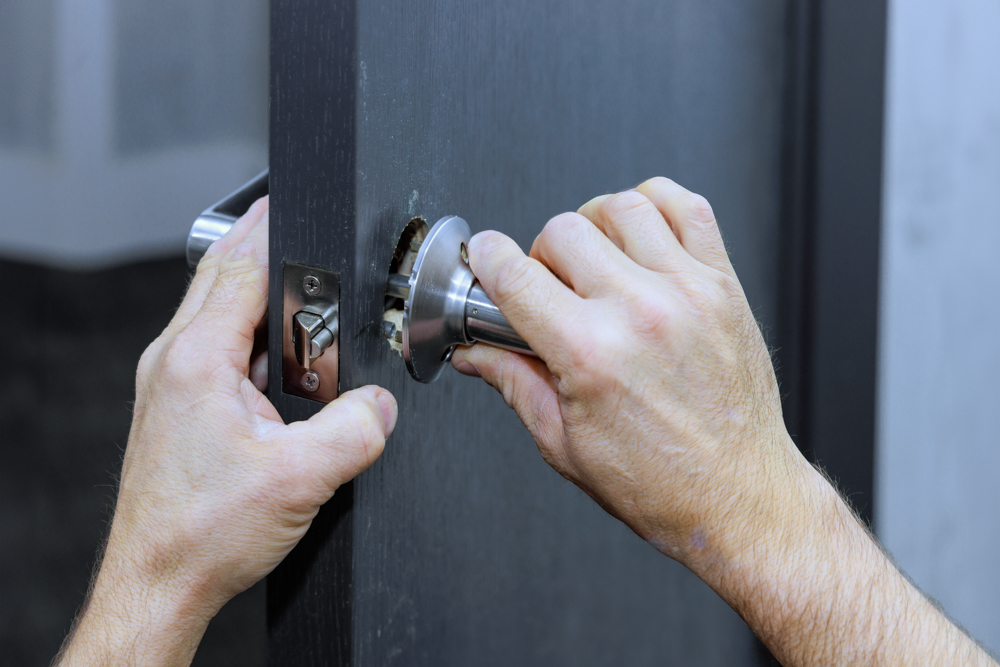 Locksmith installing door latch with drill for key replacement