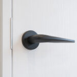 Modern black handle on white door